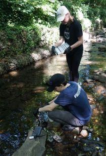 Two students using tools to examine a shallow creek