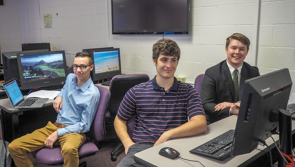 Three students sitting in the computer lab during senior capstone presentations