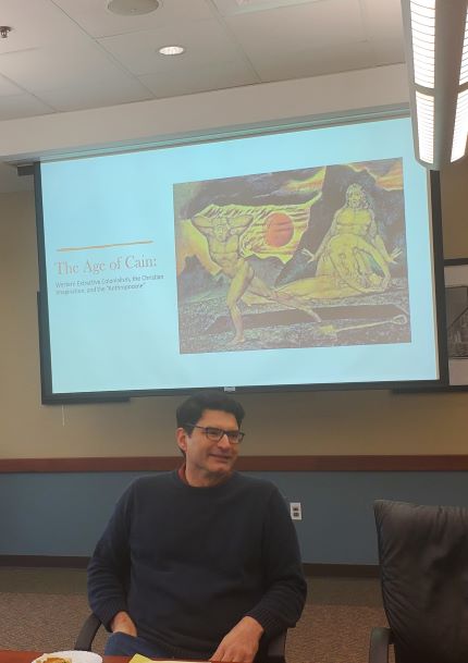 Dr. Daniel Castillo sitting at table in front of title slide