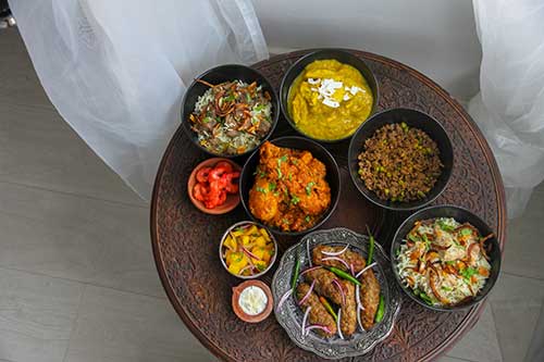 Multiple bowls of different Indian food on a platter