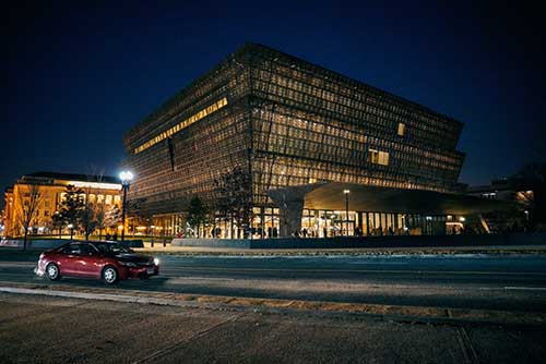 A street view of the National Museum of African American History and Culture lit up at night