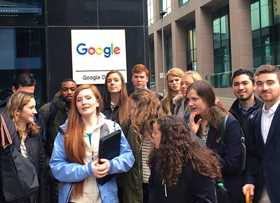 Students posing for a photo in front of a Google building