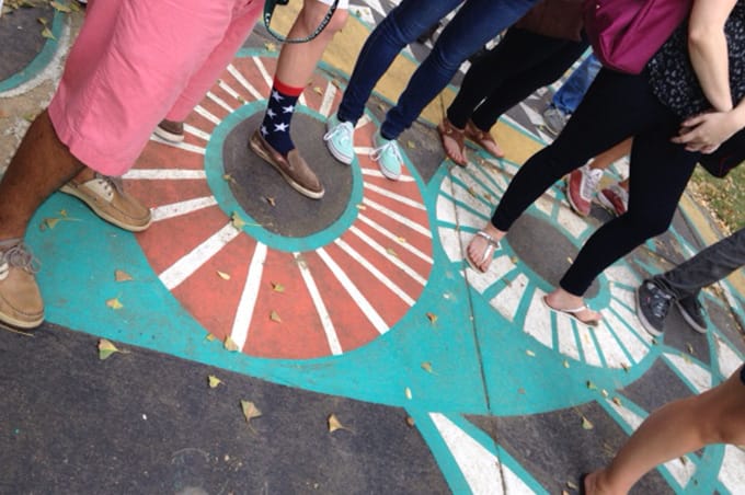 Students standing on and looking at a mural on the ground