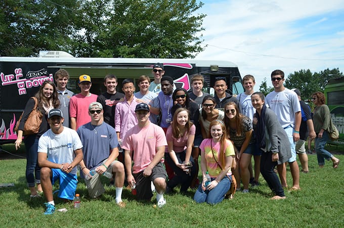 A large group of students posing for a photo in front of a food truck