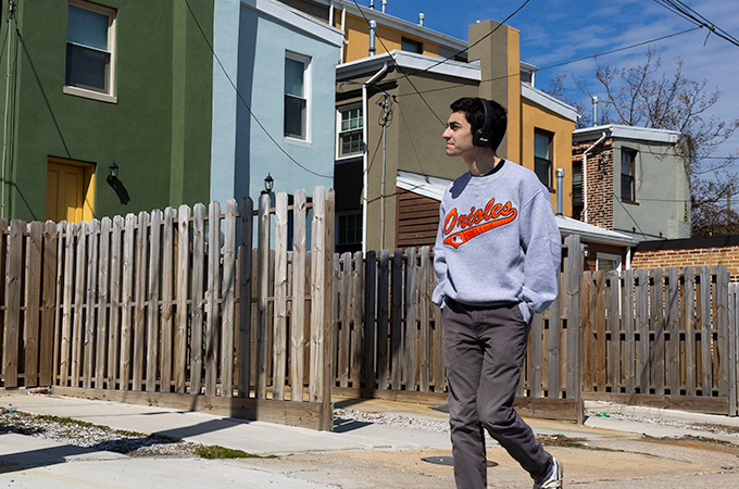 Andrewing walking through a neighborhood with rowhomes in Baltimore