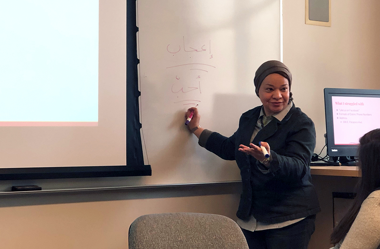 Hassan teaching her class as she writes on the whiteboard.