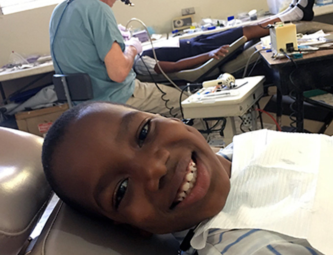 A Haitian child sits in a dentist chair smiling
