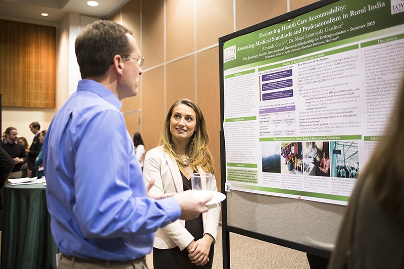 A student presenting a poster speaks with a professor