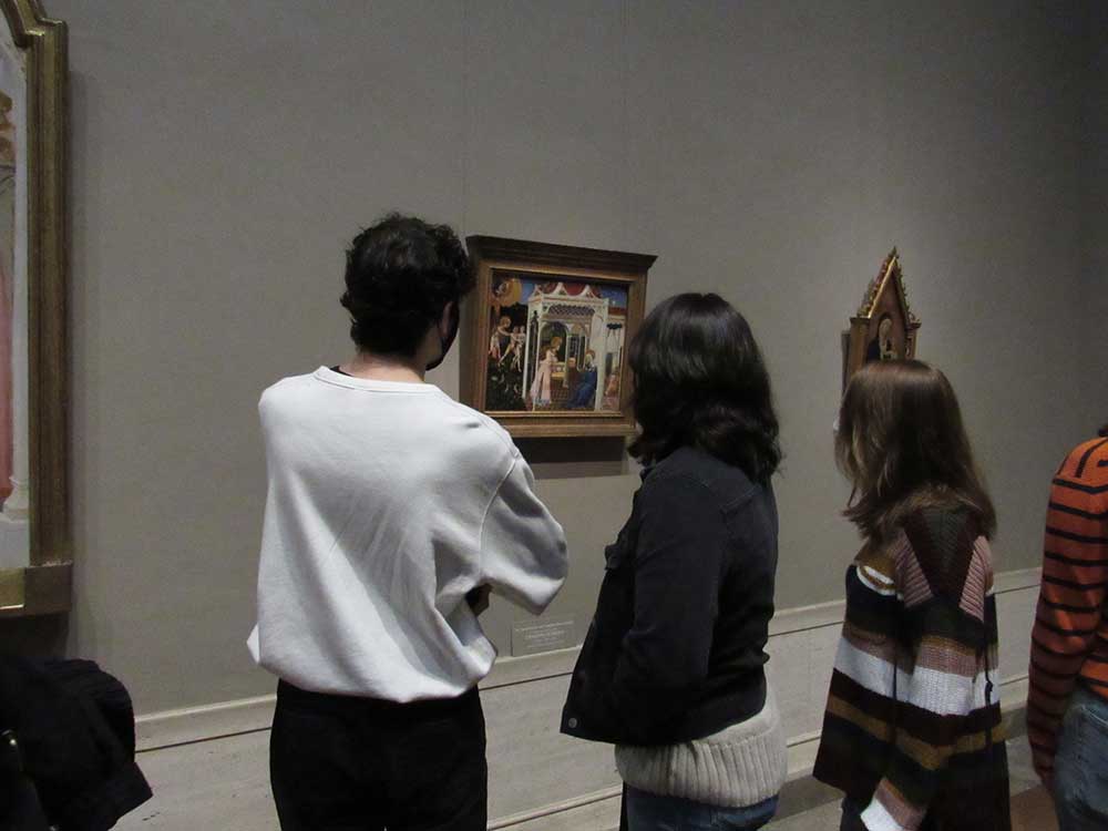 Three honors students examining a painting on a wall at The Met