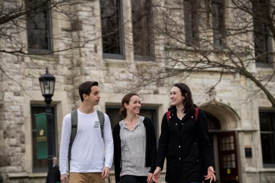 Dr. Theresa DiDonato walking and conversing with two students on the quad behind Beatty Hall.