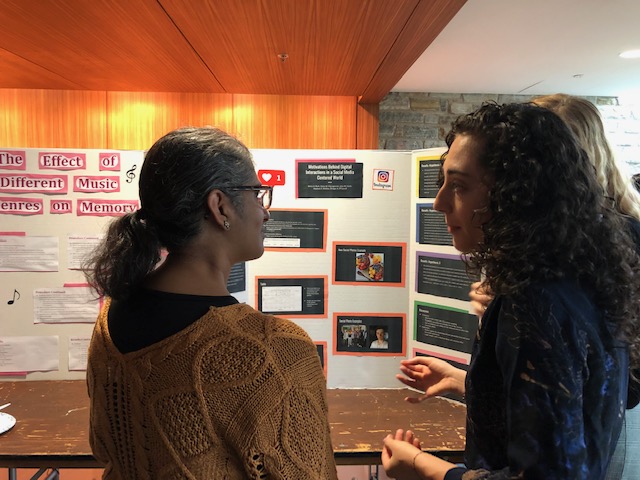 Two individuals discussing and commenting on the contents of a poster presentation.