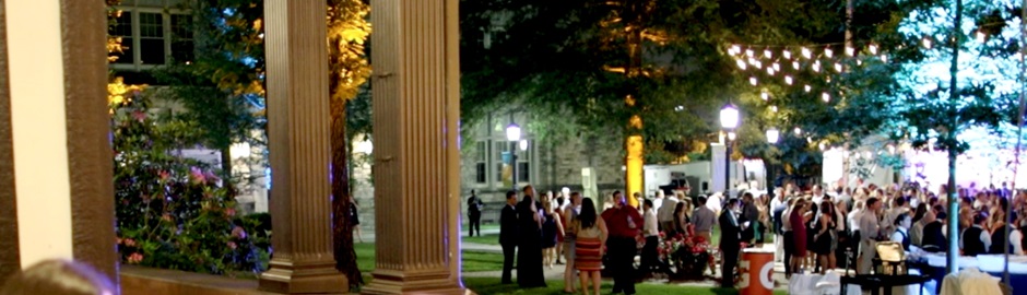 Event attendees on Loyola's academic Quad in the evening with strings of lights hanging from trees above them