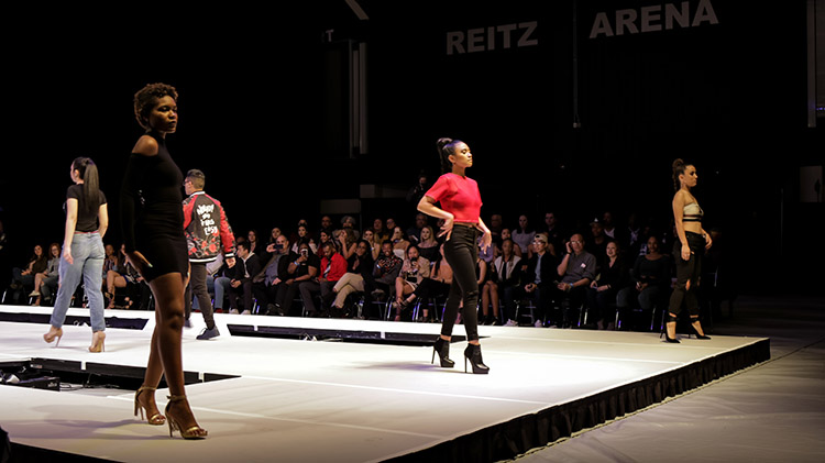 Three female models lined across the top of the catwalk