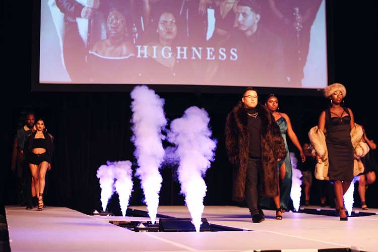 Male and female models walking down the runway dressed in a dark color scheme