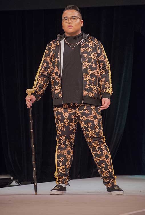 Male model posing on the catwalk with a cane and bold printed sweat suit