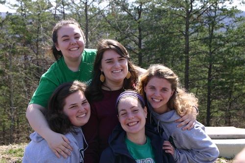 Four students on Women's Retreat smiling outside with forest in the background