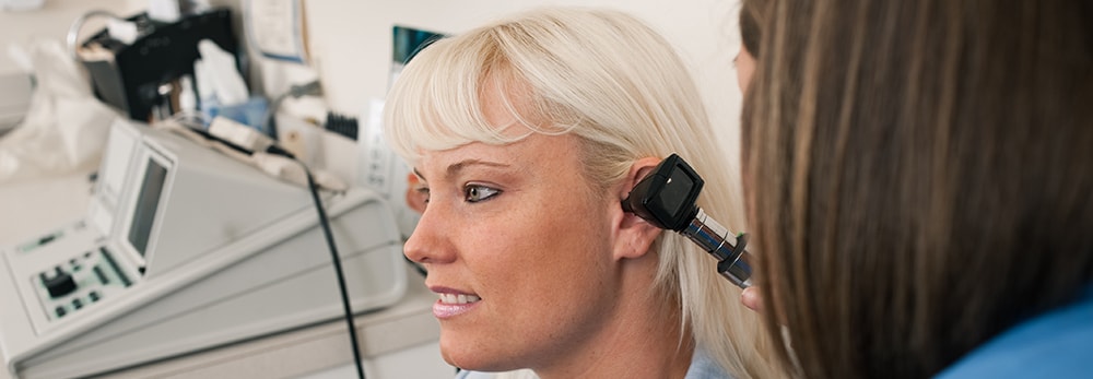 A woman having her ear inspected with an otoscope