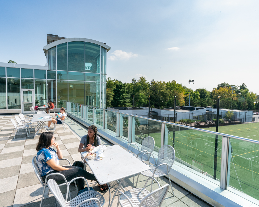 Students sit at roof top tables overlooking Diane Geppi Aikens field