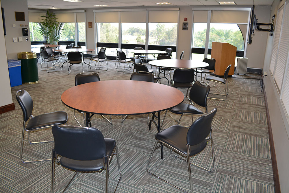 Round tables with chair and a wall of windows in the back overlooking campus