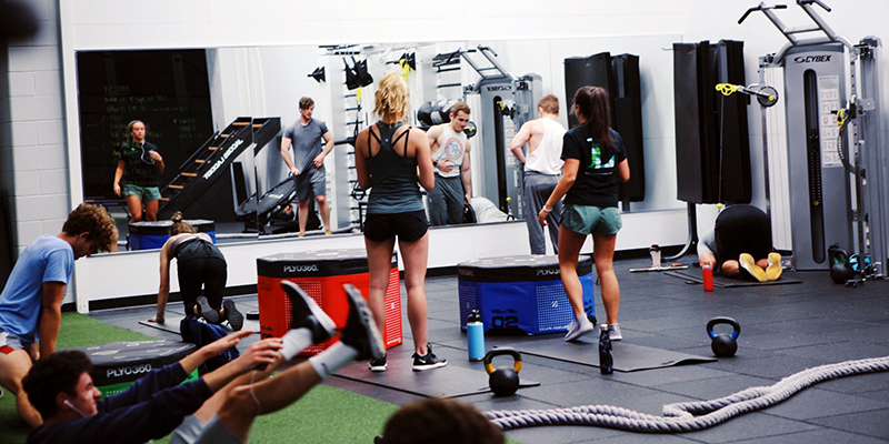 Male and female students exercising in the functional fitness area