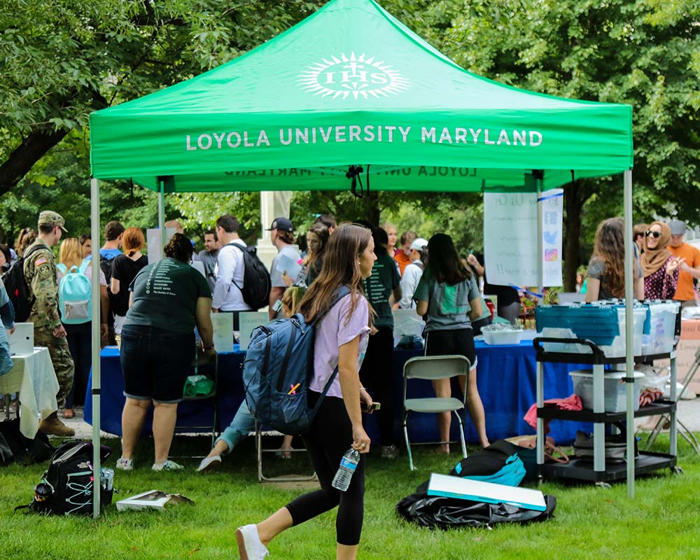 A view of students perusing the activities fair from under a green tent