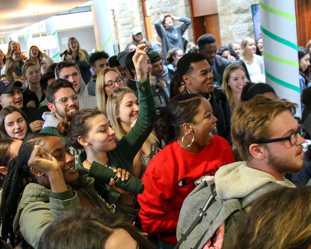 Students crowded in the Student Center smiling and cheering