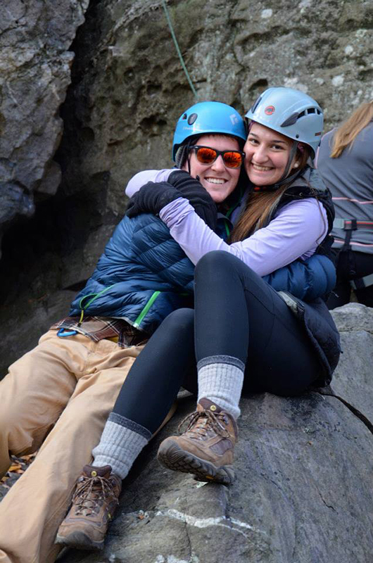Two students hug while taking a break during rock climbing
