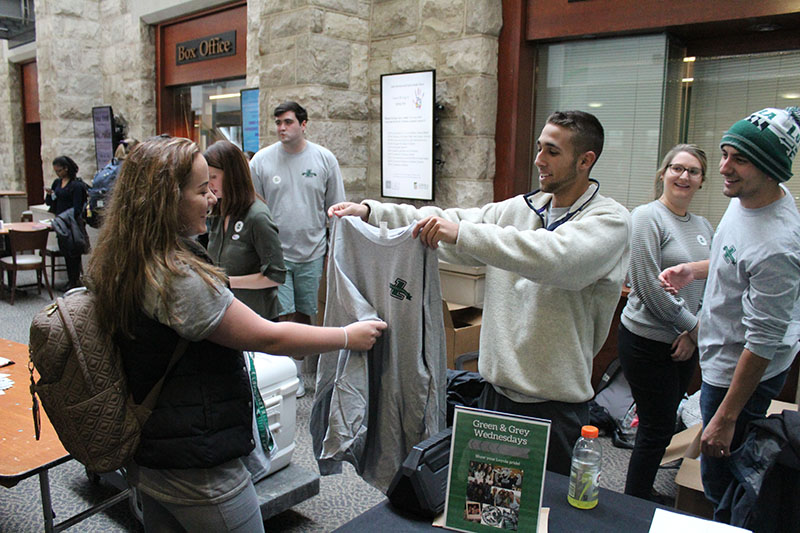 A student receives a Loyola shirt from a student manning a table in the Student Center