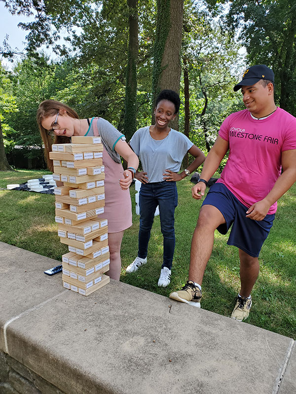 Students play a jumbo version of Jenga outdoors at Loyola's Milestone Fair