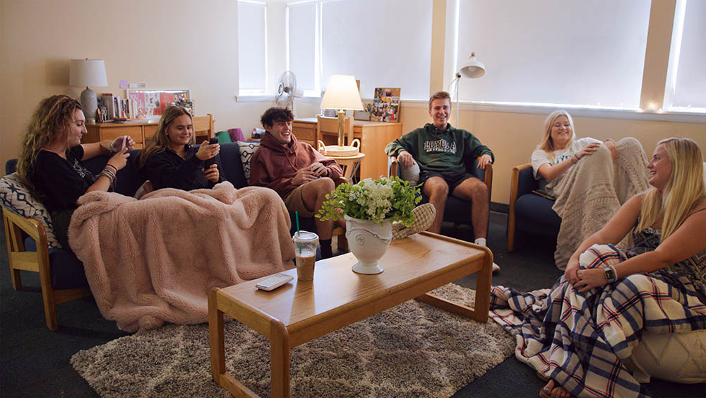 A group of students hanging out sitting on couches in a decorated dorm room