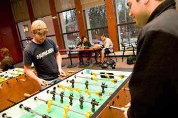 Students playing a game of foosball in Newman lounge