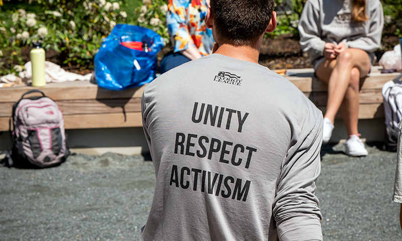 Male student wearing a shirt with the words "unity, respect, activism"