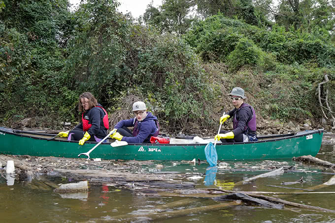 Students on canoe scooping water pollution