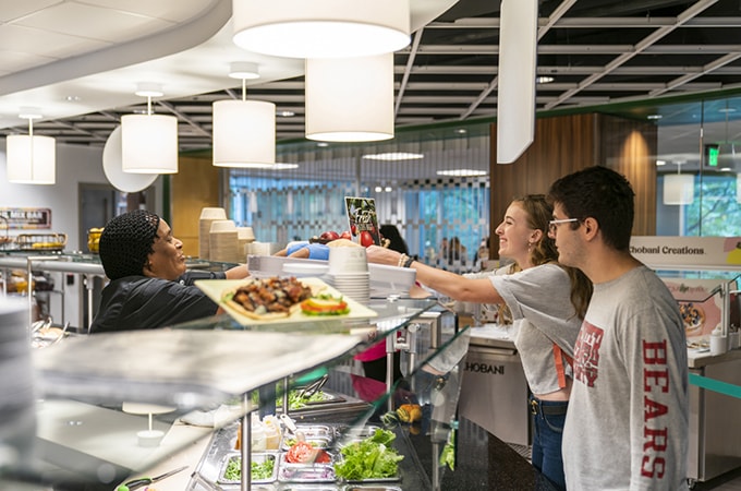 Students receiving food from a worker at one of the on-campus dining halls