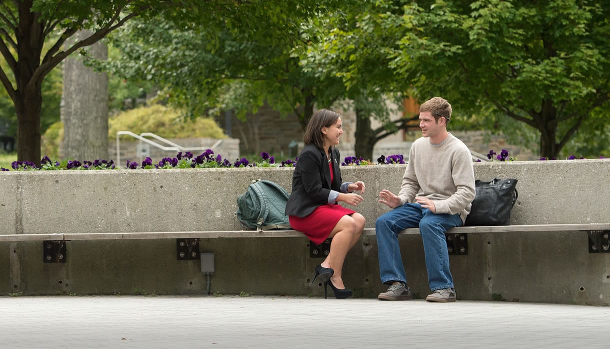 Students talking on a concrete bench outside