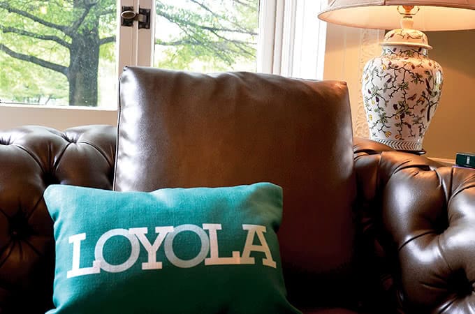 Close-up of a green Loyola pillow sitting atop a brown leather couch