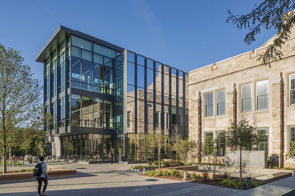 The glass exterior of the Fernandez Center next to the stone architecture of Beatty Hall