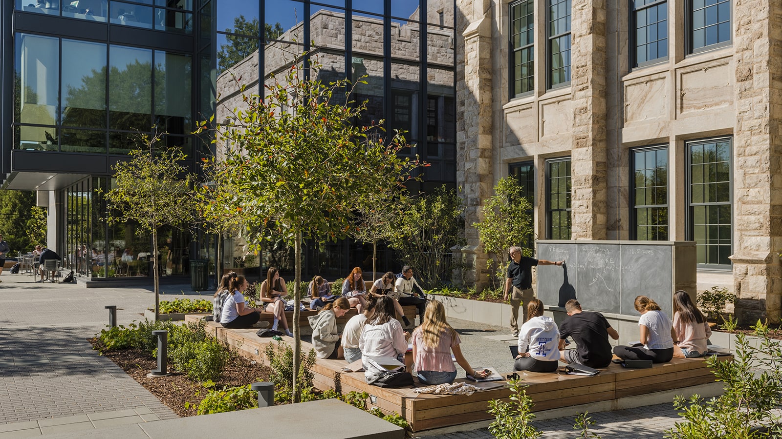 Students sitting outside the new Fernandez Center listening to a lecture on a sunny day