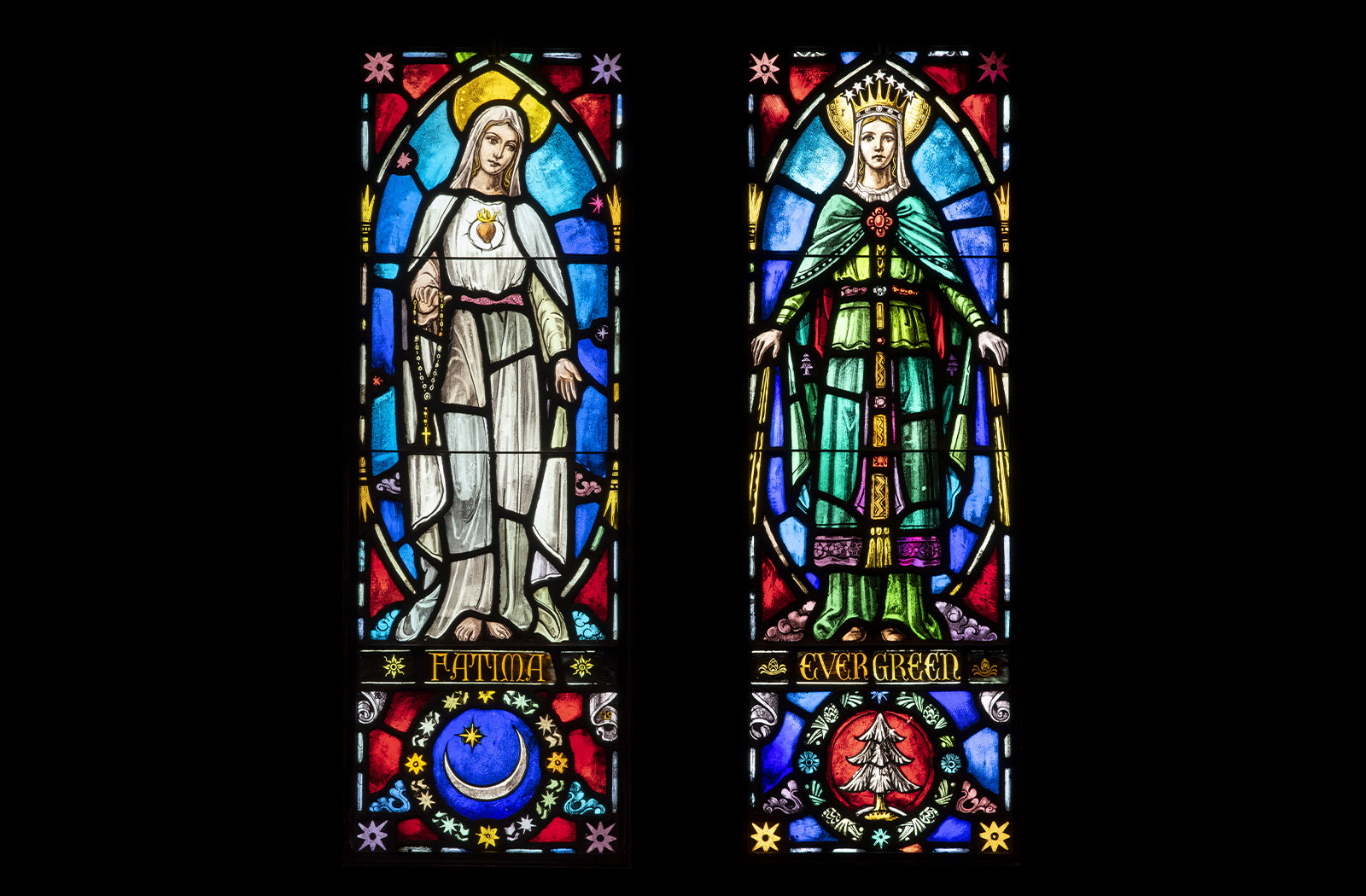 Two colorful stained glass panels of Our Lady of Fatima and Our Lady of Evergreen
