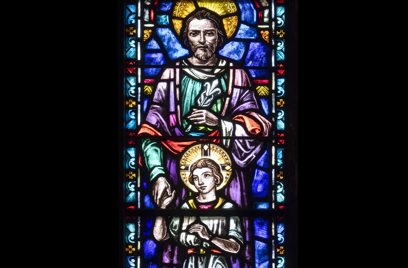 Detail photo of a colorful stained glass panel depicting Jesus and Joseph