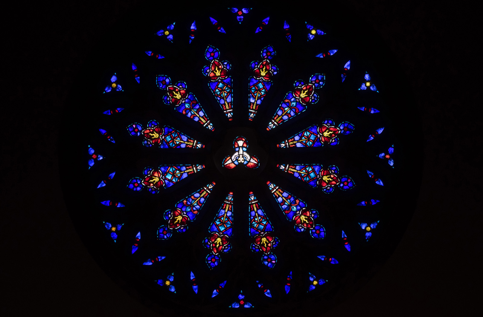 Detail photo of a colorful stained glass panel called the Rose Window