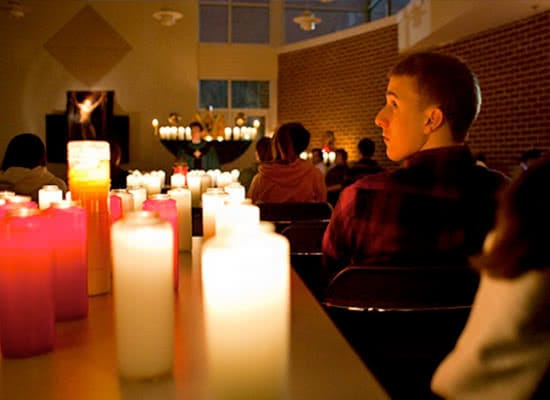 A male student sitting next to lit candles