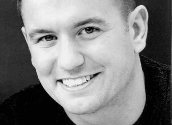 Black and white photo of a smiling Sean Lugano.