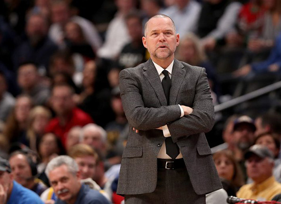 Mike Malone crosses his arms at the stadium, seemingly watching the players.
