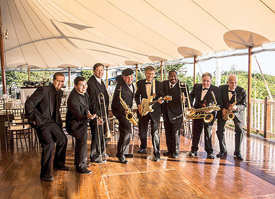 Swing band standing in a semi-circle and holding their instruments.