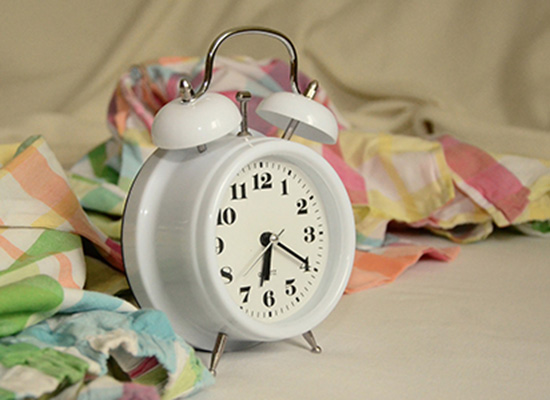 Small, white clock surrounded by pastel and white fabrics.