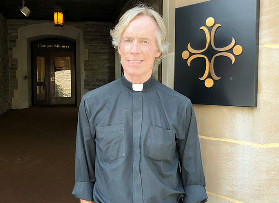 Fr. Jack Dennis in front of Alumni Chapel office and class entrance.