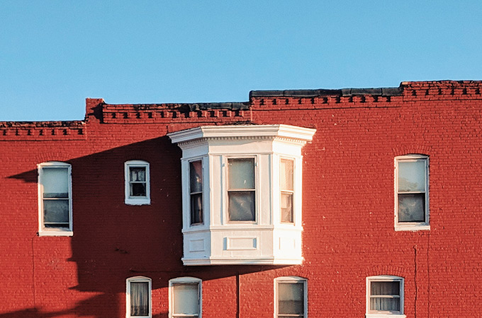 A building with red bricks and a white window set in front of a blue sky