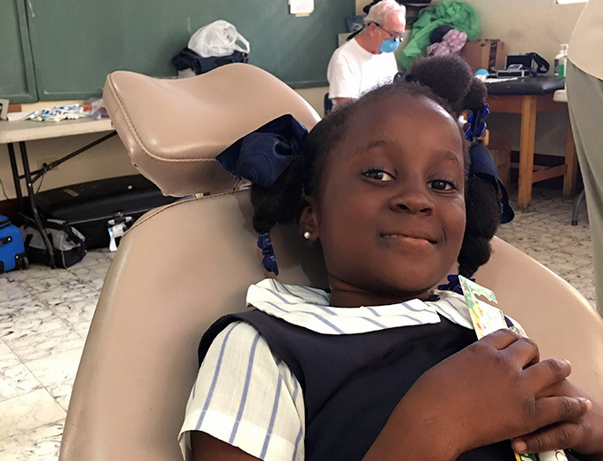 A Haitian child sits in a dentist chair smiling