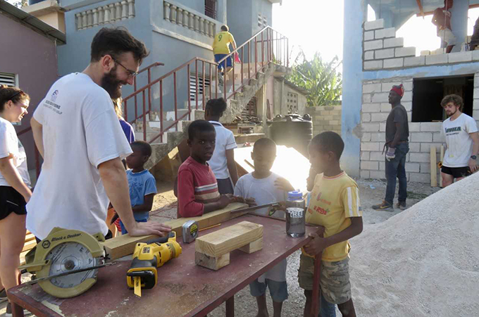 Loyola students working with Haitian school children outside.